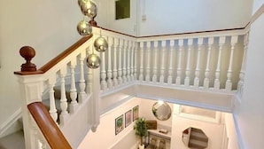 A multi-level interior with a staircase, white railings, and a skylight. - The Bay Apart-Hotel (Southwold)