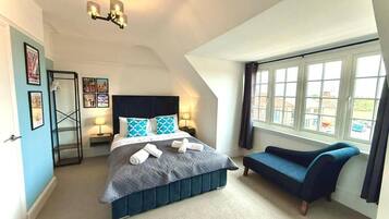 Un dormitorio con cama, mesitas de noche, ventana y vistas al exterior.