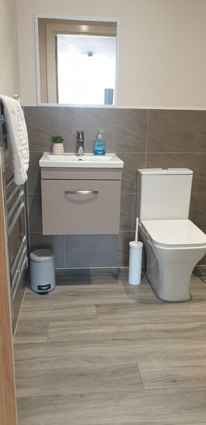 A bathroom with a toilet, sink, and a trash bin. - Modern 2 Bedroom Apartment /Mancehster city Centre/ Sleeps 5. (Manchester)