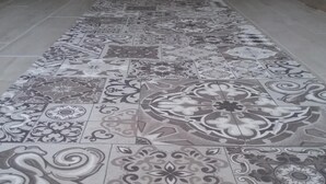 Un couloir doté d’un sol carrelé à motifs et d’une porte au fond.
