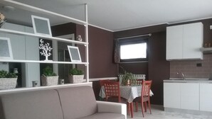 Un espacio habitable moderno con sofá, mesa de comedor, sillas y zona de cocina.