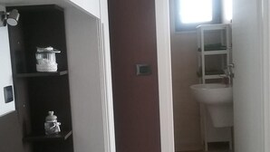 Un dormitorio con cama, mesita de noche, armario y baño visible a través de una puerta abierta.