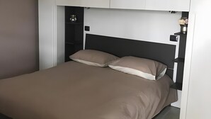 A bedroom with a bed, built-in wardrobe, and a bedside table.