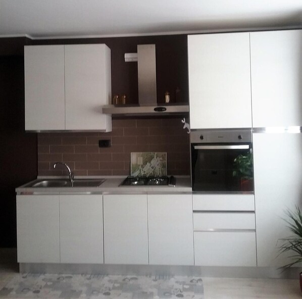 A kitchen with white cabinets, a stove, and a sink.