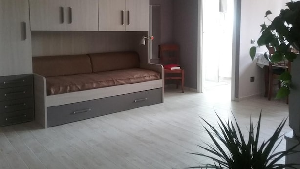 A modern living room with a sofa, a chair, a dining table, and a large plant.