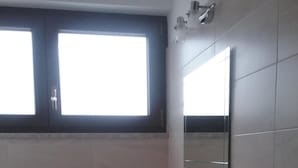 A bathroom with a white sink, a mirror, and a window above the sink.