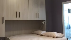A bedroom with a bed, a wardrobe, and a window.