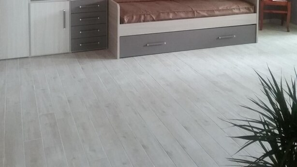 A modern bedroom with a built-in bed, storage cabinets, and a small seating area.
