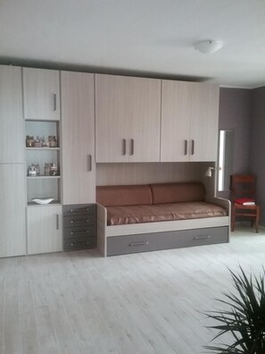 Un dormitorio moderno con cama empotrada, armarios de almacenamiento y un pequeño rincón de descanso.