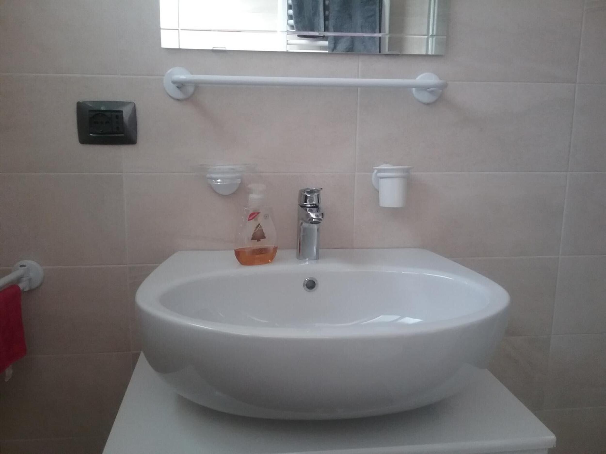 Une salle de bain avec un lavabo blanc, un miroir au-dessus et un porte-serviettes à gauche.