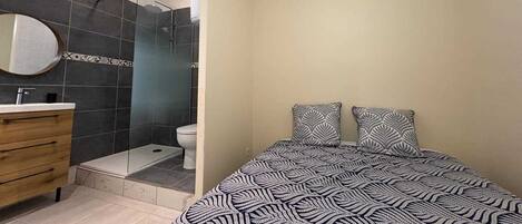 A bedroom with a bed, two pillows, a bedside table, and a mirror.