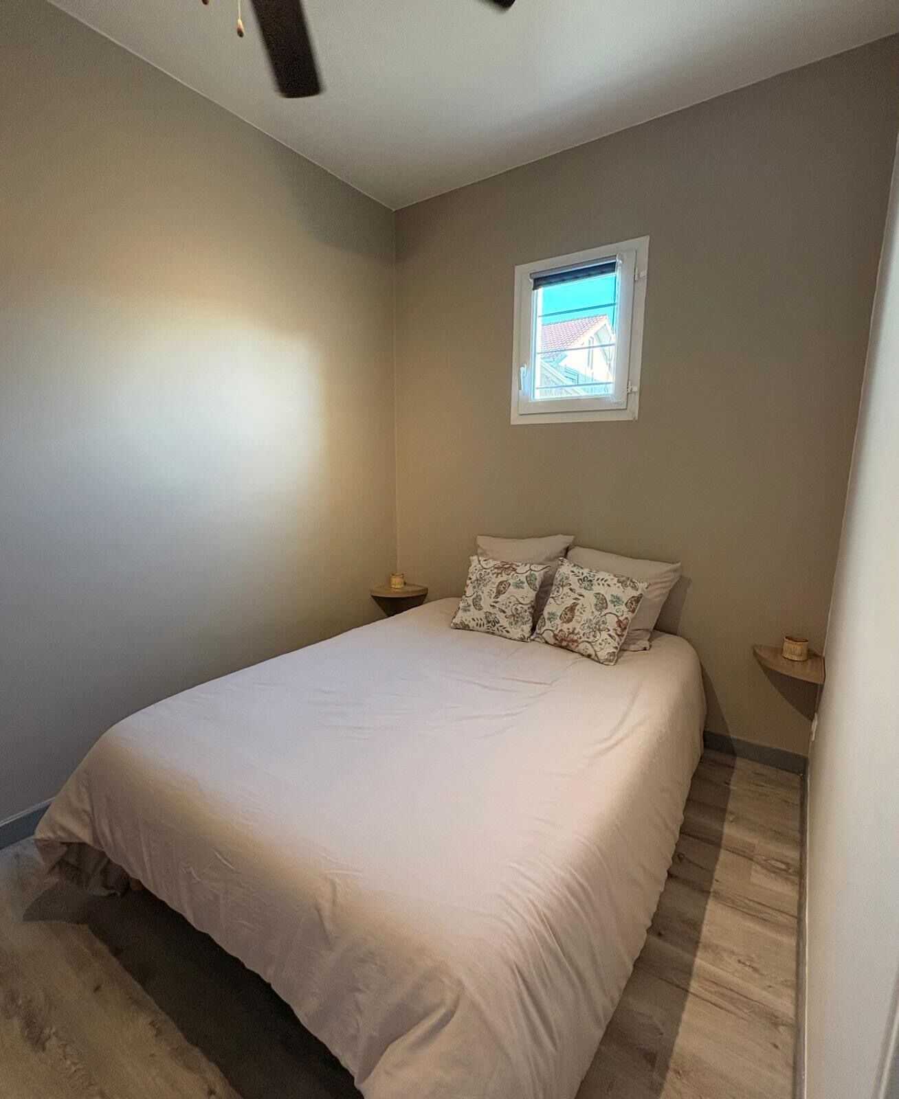 Un dormitorio con una cama, dos mesitas de noche, una ventana y una lámpara.