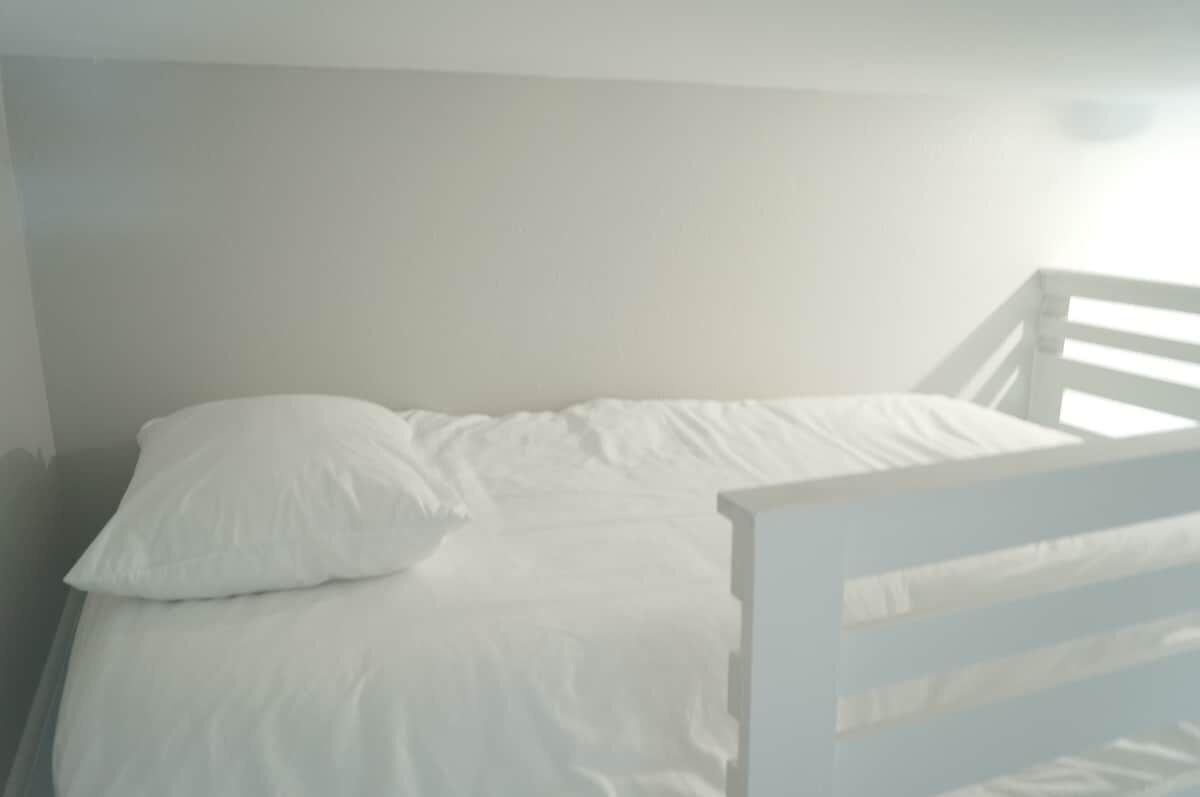 A single bed with white bedding in a room with plain white walls.