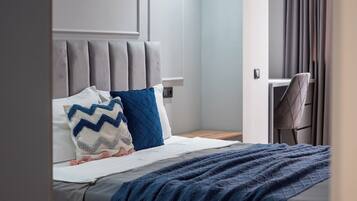 A modern bedroom with a bed, a nightstand, a desk, and a chair.