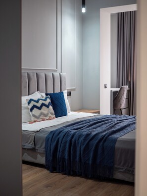A modern bedroom with a bed, a nightstand, a desk, and a chair. - Comfort City Residence with beatiful vew (Almaty)