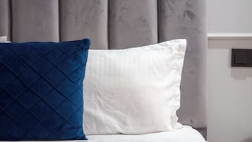 A bed with a grey upholstered headboard, white and blue pillows, and a blue bedspread.