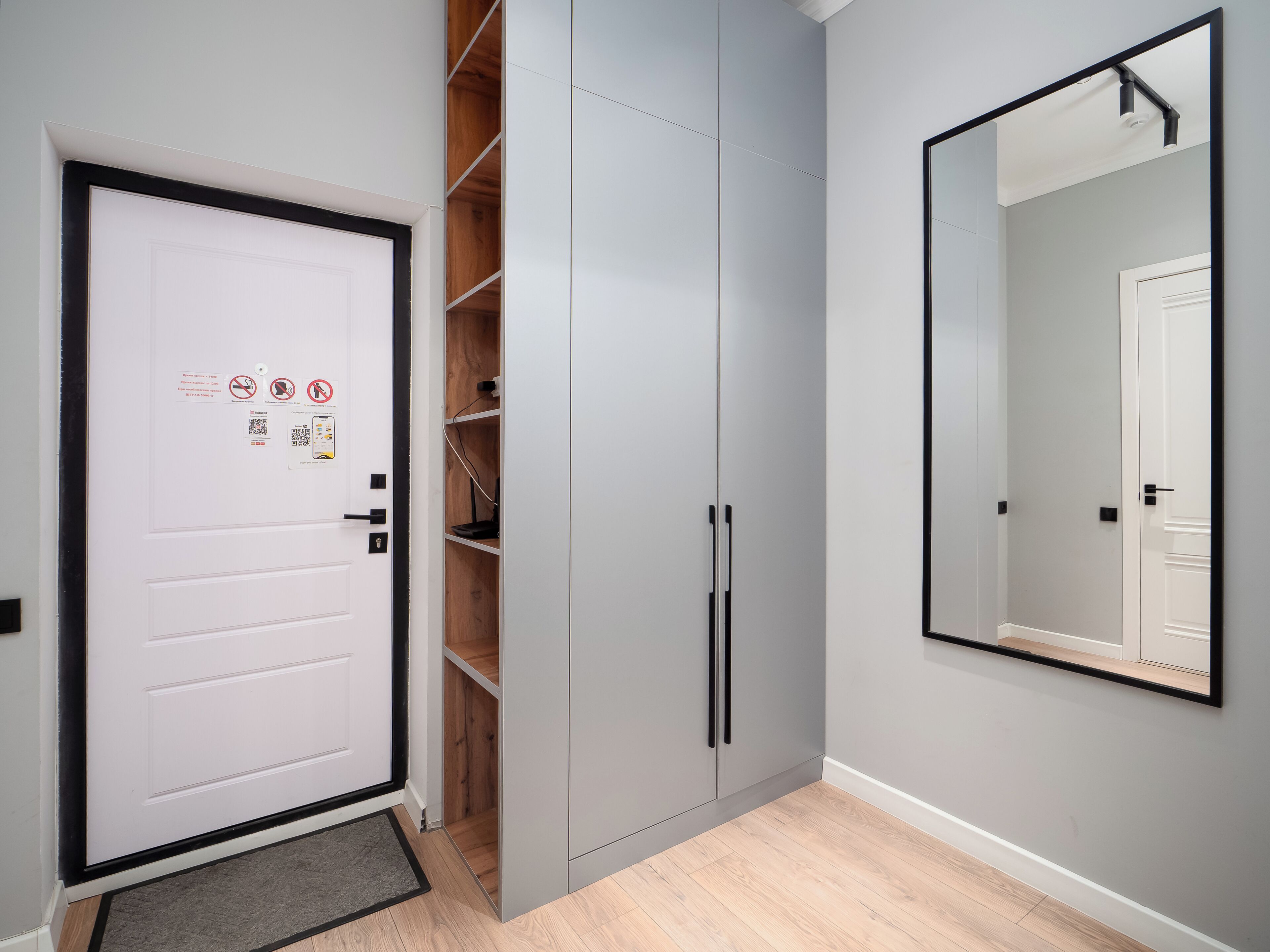 A room with a white door, grey wardrobe, and a mirror on the wall.