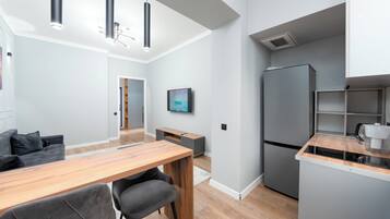 Una cocina moderna con refrigerador integrado, un comedor con mesa y sillas de madera, e iluminación colgante.