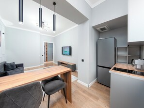 Una cocina moderna con refrigerador integrado, un comedor con mesa y sillas de madera, e iluminación colgante.