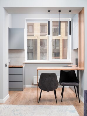 A modern kitchen with a window, wooden countertop, two chairs, and a built-in cabinet. - Comfort City Residence with beatiful vew (Almaty)