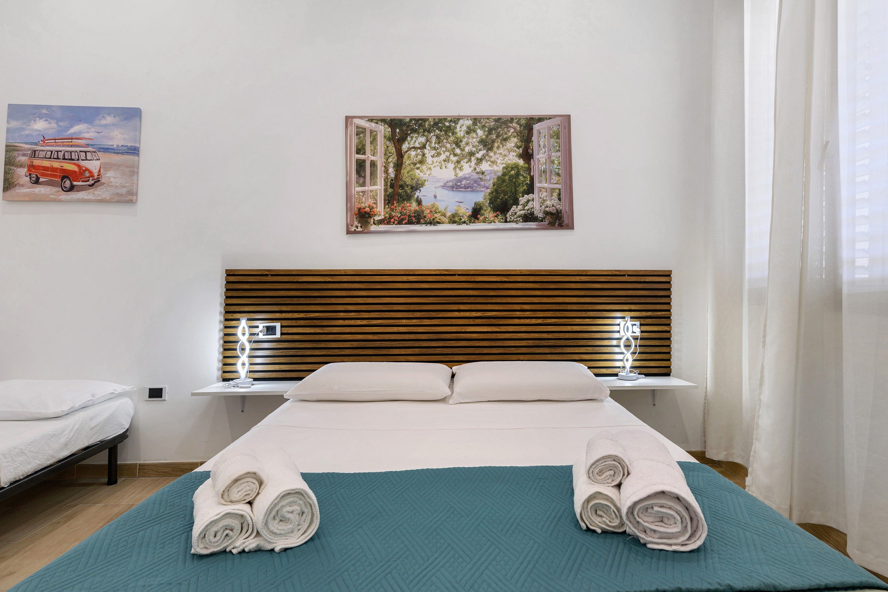 Une chambre d’hôtel avec un lit, une fenêtre donnant sur un paysage et un tableau accroché au mur.