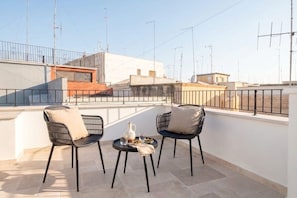 A rooftop terrace with two chairs and a small table, a clear view of the cityscape, and a railing. - Palazzo Vanese Sus | Boutique Stay with Private Rooftop Terrace (Bari)