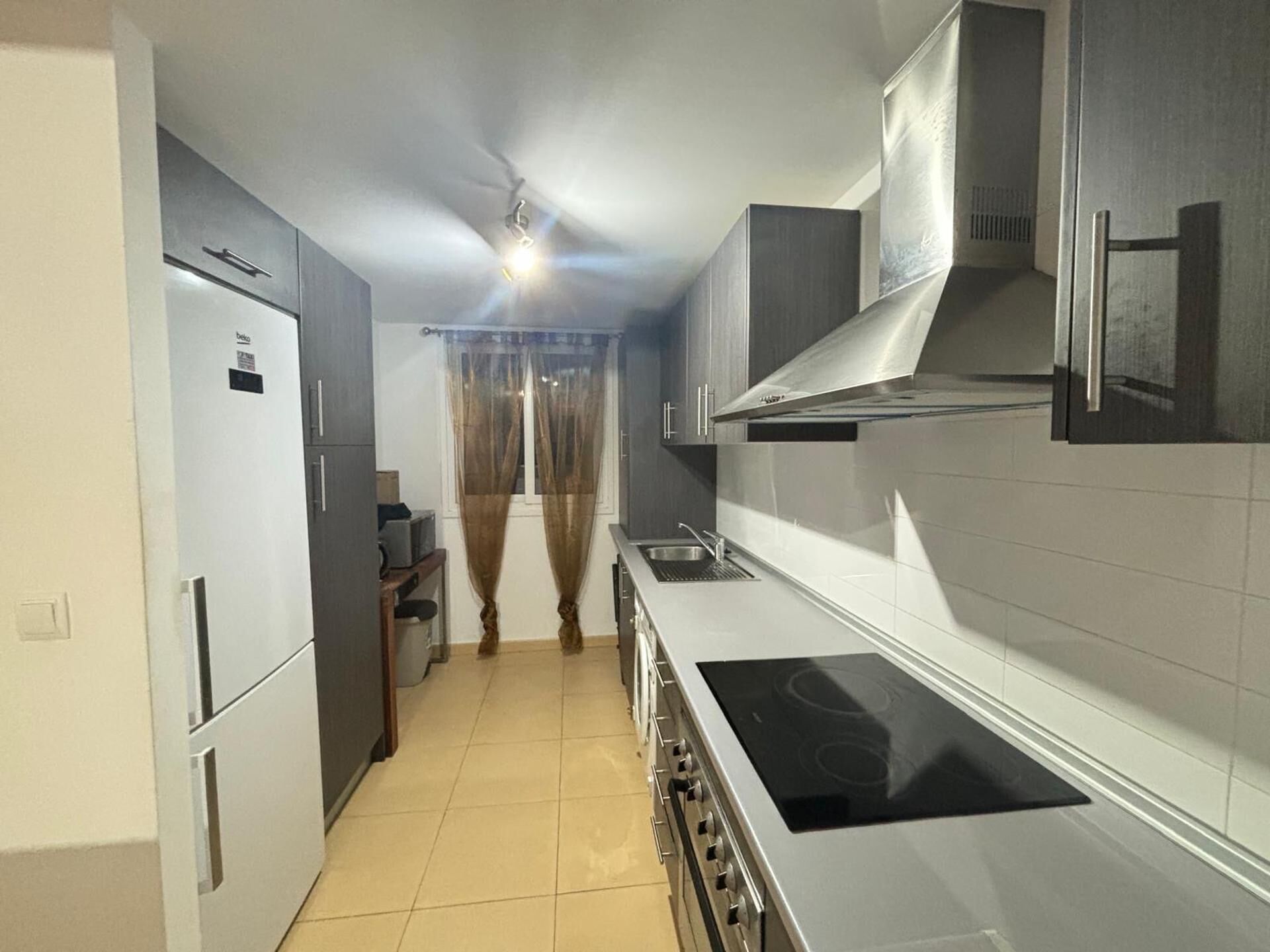 A modern kitchen with a built-in oven, stainless steel cabinets, and a tiled backsplash.