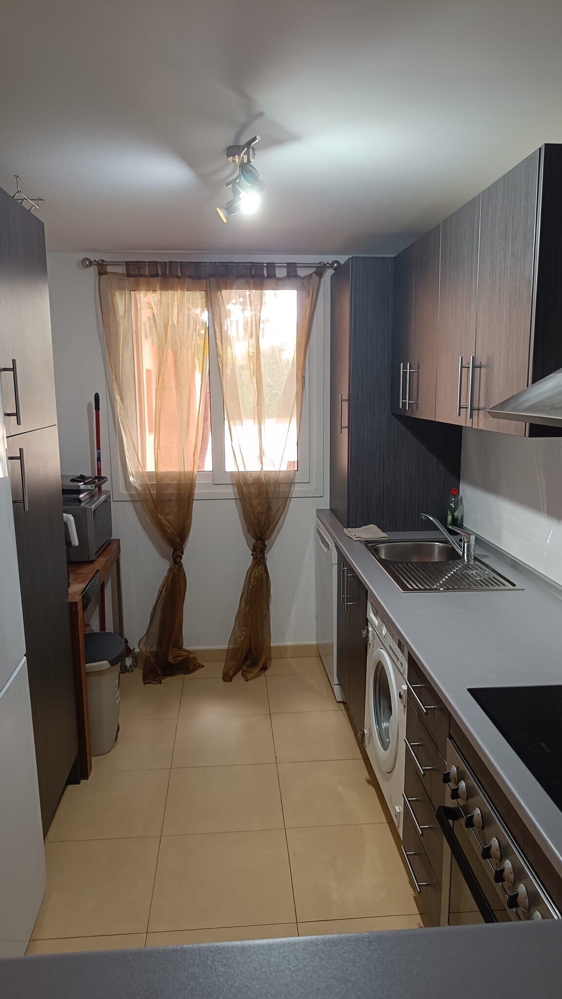 A compact kitchen with a washing machine, a sink, and a stove.