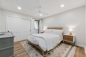 A bedroom with a bed, bedside tables, a dresser, a ceiling fan, and a window with curtains. - 3BR Beachside Villa with Community Pool, Short Walk to the Beach (Hilton Head Island)