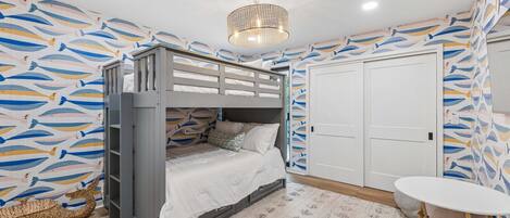 Une pièce avec un lit superposé, une petite table et une porte.