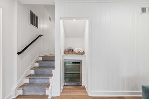 Eine Treppe mit Holzstufen und einem grauen Teppich, die zu einer weißen Wand mit einem eingebauten Backofen und einem Wäschekorb führt.