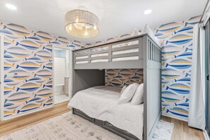 Ein Schlafraum mit Etagenbetten, einer Deckenleuchte und einer Wand mit Muster.