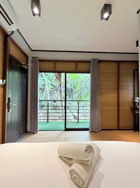 A hotel room with a large bed, a view of a garden, and a sliding door.