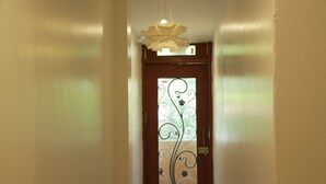 Um corredor com uma porta de madeira, com um painel de vidro decorativo com motivos florais.