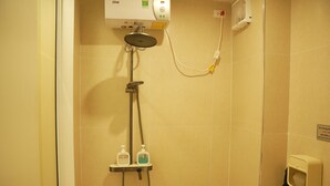 Um chuveiro com um chuveiro manual, um painel de controle fixado na parede e dois frascos de shampoo e condicionador.