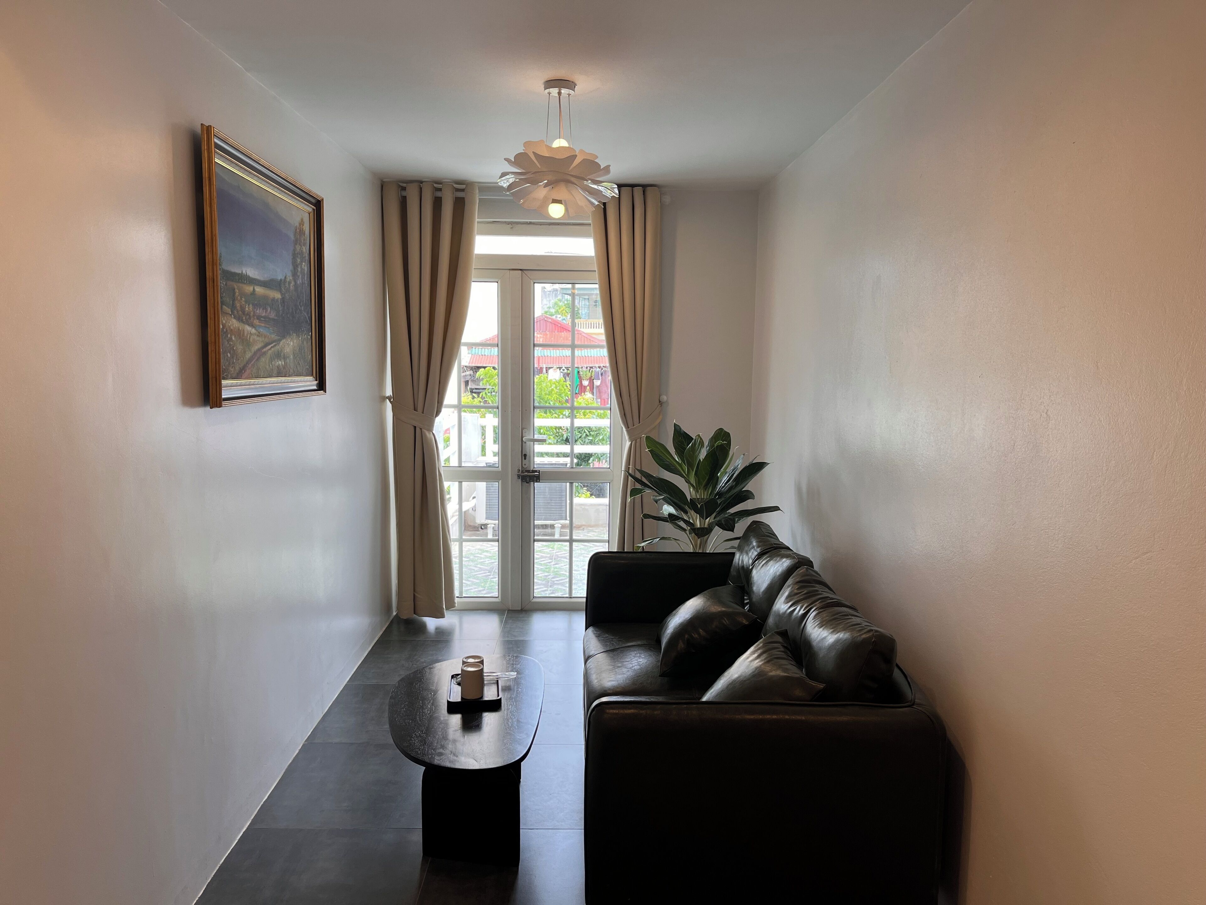 Un salon moderne avec un canapé en cuir, une table basse, un tableau et une plante.