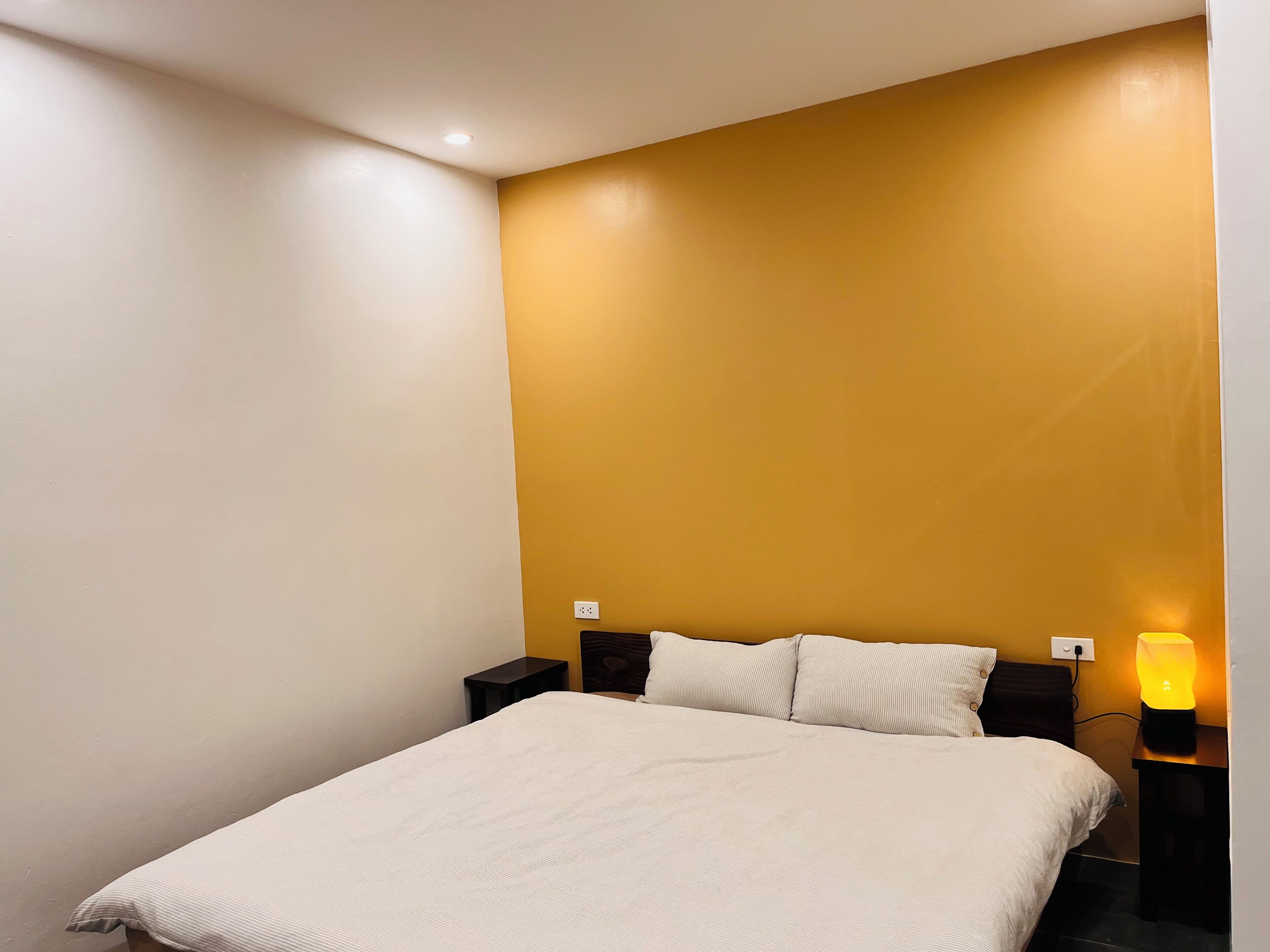 Une chambre à coucher avec un lit, deux tables de chevet et une lampe fixée au mur.