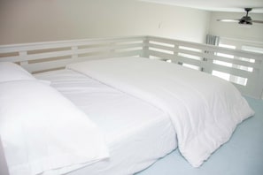 Ein Bett mit weißem Kopfteil und Fußteil, einer weißen Matratze und einem hellblauen Matratzenbezug.