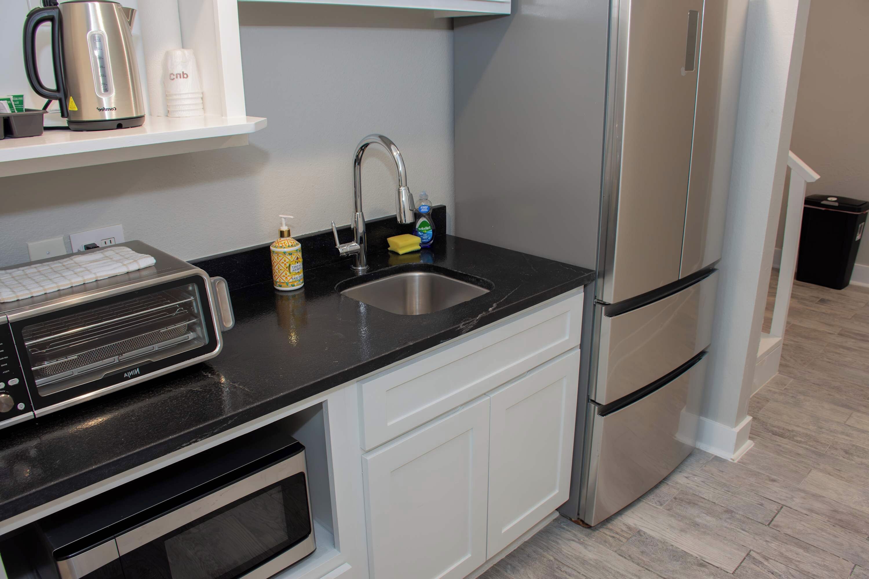 A kitchen with a toaster, kettle, sink, and stainless steel appliances.