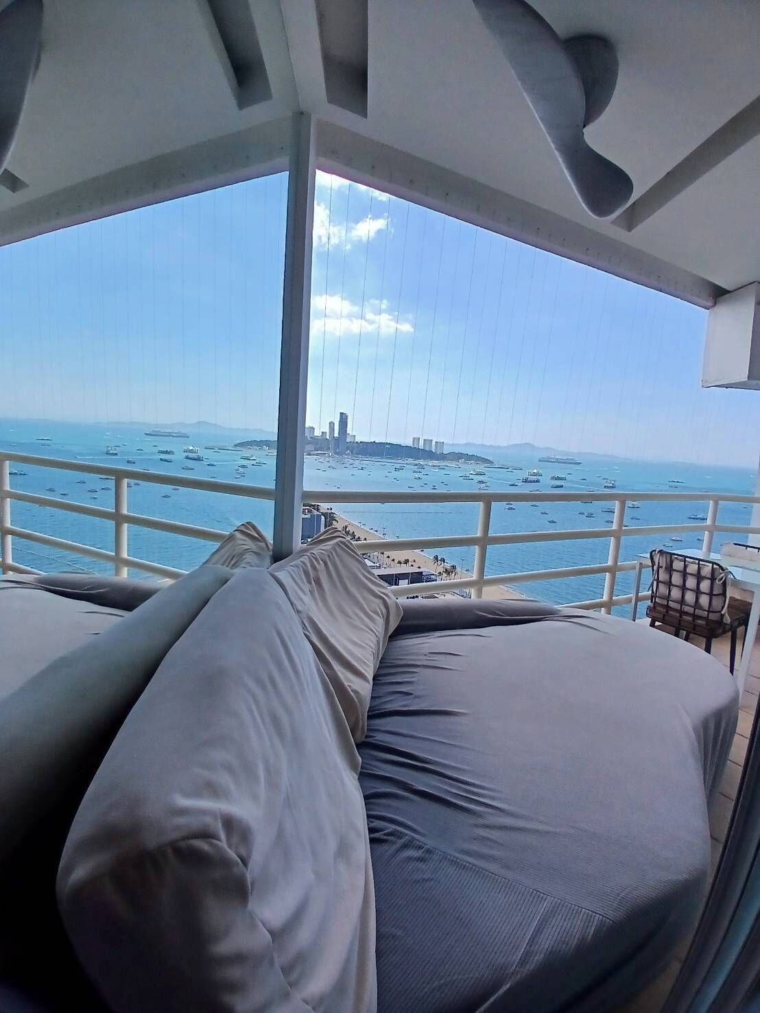 A balcony with a view of the sea and a cityscape.