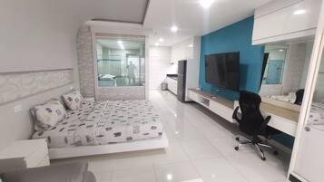 A modern bedroom with a bed, a desk, a chair, and a TV.