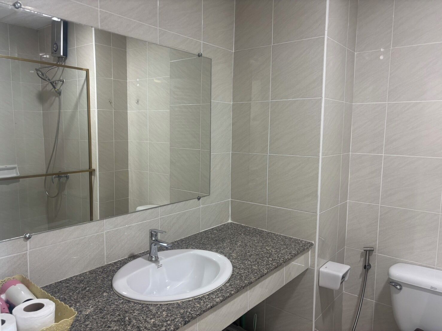 Een badkamer met een wit wastafel, spiegel en douche.