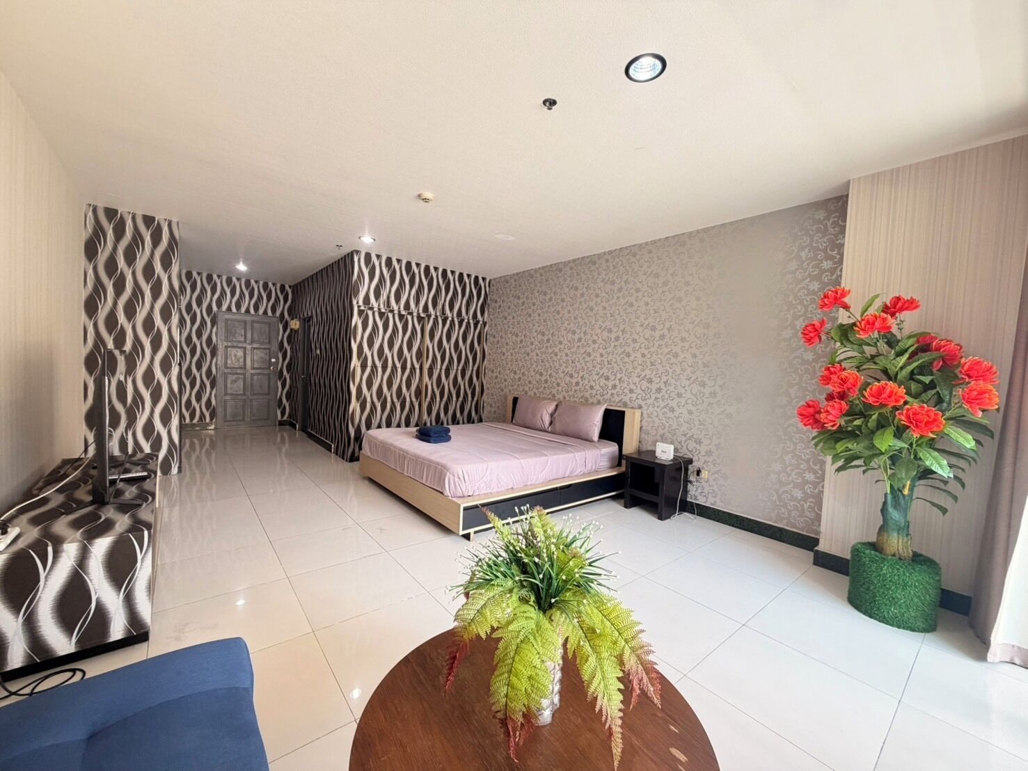 Une chambre d’hôtel moderne, équipée d’un lit, d’une table de chevet, d’une petite plante et d’un vase décoratif.