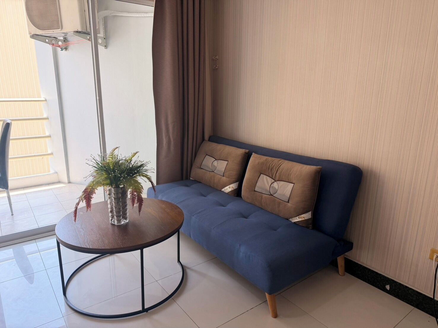 A modern living room with a blue sofa, a round table, and a potted plant.