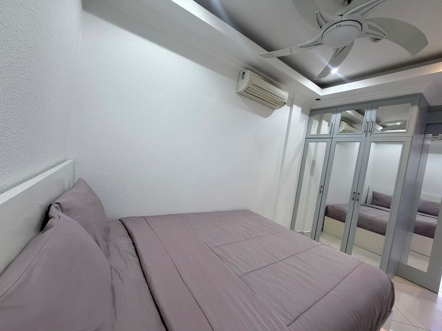 A bedroom with a bed, a ceiling fan, an air conditioning unit, and a sliding glass door closet.