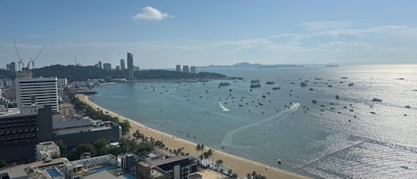 A coastal cityscape with a beachfront, buildings, and boats on the water.