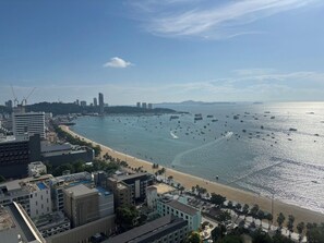 A coastal cityscape with a beachfront, buildings, and boats on the water.