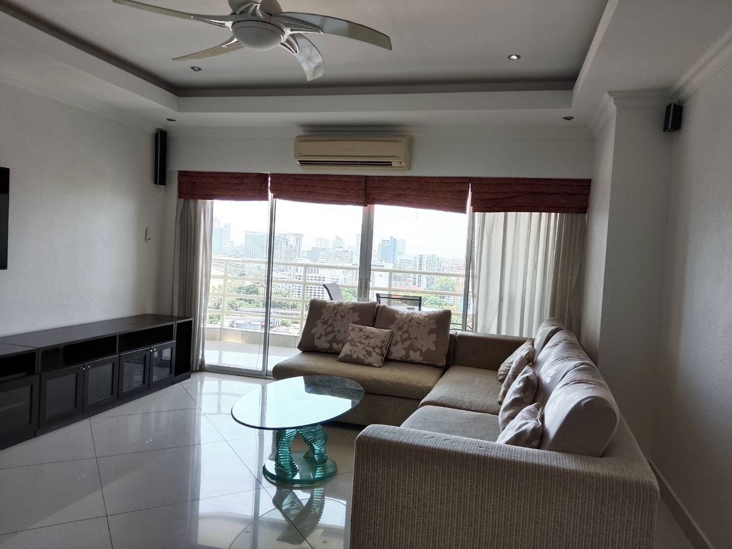 A modern living room with a sofa, a glass coffee table, and a ceiling fan.