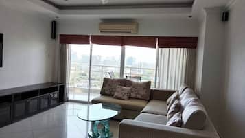 A modern living room with a sofa, a glass coffee table, and a ceiling fan.