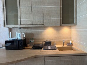 A modern kitchen with a microwave, kettle, and a coffee maker on the counter.